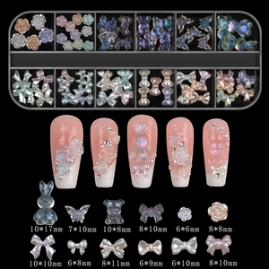 Detail of 12-grid nail art kit with aurora bows, pearls, and resin bears on black base