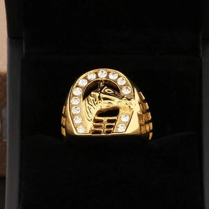Detail of a golden horse head ring set in a crystal horseshoe on a black velvet base