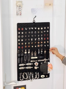 Wall-mounted black felt jewelry organizer with hooks for earrings and necklaces