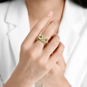 Golden sunflower ring with skull design and green zircon stones on model hand