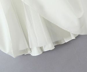Gros plan sur l'ourlet de la robe blanche montrant la doublure en tulle