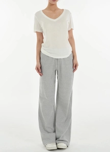 Detail of white V-neck wool t-shirt and striped wide-leg trousers on model