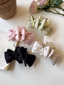 Close-up of silk bow hair claws in pink, green, cream, and black with ribbon details