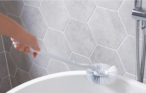 Ergonomic curved long handle toilet brush with dense bristles cleaning a bathtub edge