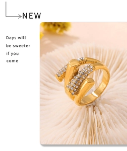 Vue détaillée bague dorée entrelacée avec strass sur support texturé blanc élégant