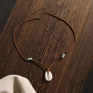 Bohemian velvet cord necklace with white shell pendant and blue beads on wood background