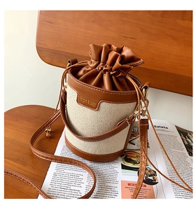 Detail of canvas bucket bag with leather drawstring closure on a vintage wooden chair