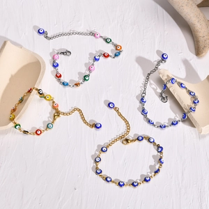 Surtido de pulseras de mal de ojo de acero inoxidable en oro y plata sobre textura blanca