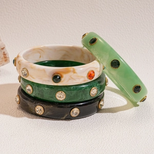 Detail of stacked acrylic cuff bracelets with inlaid rhinestones in marble and solid colors