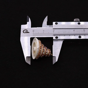 Macro-opname van een schelphanger met gekleurde strass-steentjes gemeten met schuifmaat