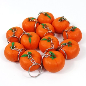 Close-up of cute realistic orange fruit keychains with silver metal chains on white background