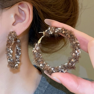Gros plan de boucles d'oreilles rondes en maille marron avec paillettes et tige en argent
