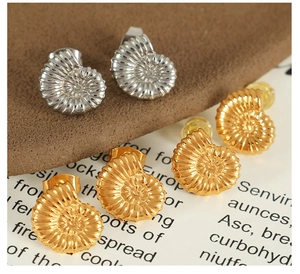Macro shot of 18K gold and silver nautical spiral earrings on a minimalist card