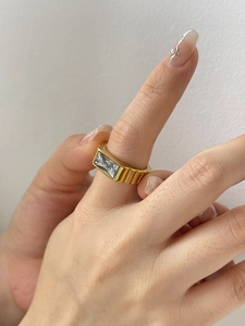 Close-up of golden textured band ring featuring a large rectangular baguette-cut zircon