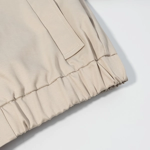Close-up of beige twill jacket detail showing elasticated hem and premium stitching