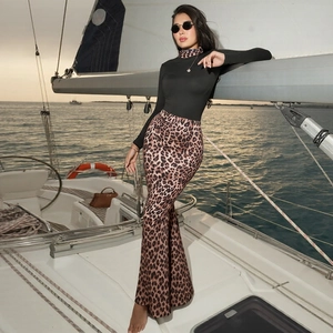 Detail of high-waist brown leopard print flared trousers paired with a black turtleneck top