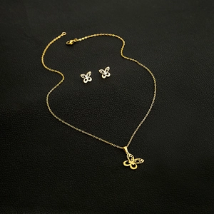 Detailed view of gold butterfly pendant necklace and matching stud earrings set