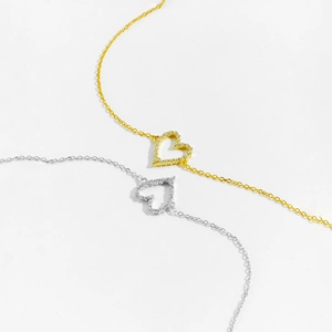 Detail of hollow heart necklaces in gold and silver finish with pavé set zircon stones