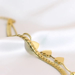 Close-up of 18K gold-plated double-layer bracelet with heart pendant on white silk