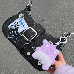 Λεπτομέρεια μαύρης τσάντας ώμου από denim με patch αστέρι, μεταλλική αγκράφα και λούτρινο.