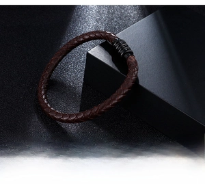 Close-up of dark brown braided leather texture and black stainless steel clasp
