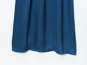 Detailed view of dark blue satin fabric texture and pleated hemline of the dress