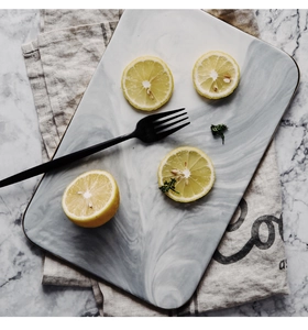 Detailed flat lay of rectangular marble texture ceramic serving tray with lemon and fork