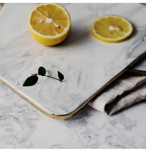 Macro view of rectangular marble ceramic tray with elegant gold metal handle and rim