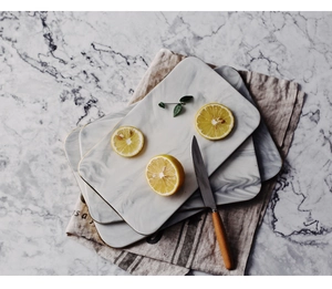 Close-up of rectangular marble ceramic plates with gold rims on a textured marble surface