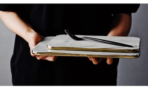 Detail of marble pattern ceramic tray with gold rim held by hands in close-up shot