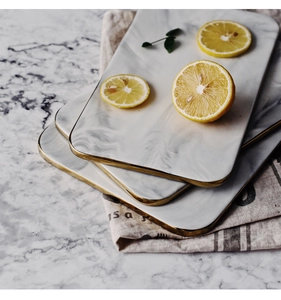 Detail of grey marble ceramic tray with gold rim layered on a linen napkin with lemon