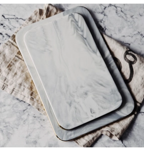 Detailed top view of marble ceramic trays with elegant gold edges on a linen napkin
