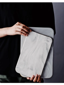 Detail of marble pattern ceramic trays with gold trim shown in hand for scale