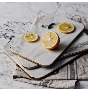 Detail of rectangular marble ceramic trays with gold edges and fresh lemon slices
