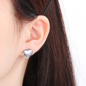 Close-up of model wearing polished silver heart stud earring in stainless steel