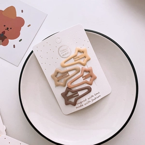 Close-up of four star-shaped matte hair clips in earth tones on a display card