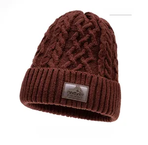 Dettaglio del berretto invernale bordeaux in maglia a trecce con patch in pelle