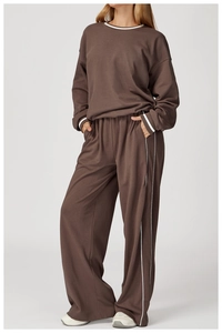Détail du survêtement marron foncé avec rayures blanches contrastées sur le pantalon large