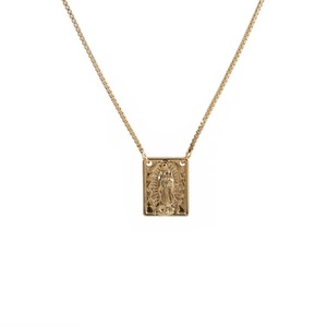 Detail of gold necklace featuring a rectangular pendant with embossed figure on a fine chain