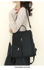 Detail view of black nylon backpack with quilted diamond pattern and metal zipper on model