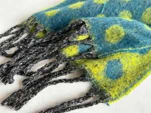 Close-up of soft cashmere-feel scarf with yellow and blue polka dots and black tassels