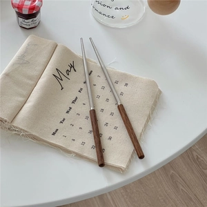Close-up of retro wooden handle stainless steel chopsticks on a minimalist fabric mat