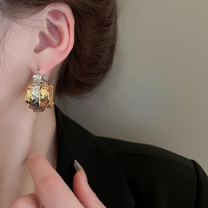 Close-up of two-tone gold and silver hammered metal hoop earrings worn by a model