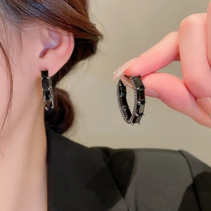 Détail macro de boucles d'oreilles créoles avec zircons noirs rectangulaires et bordure perlée