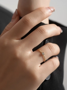 Close-up of minimalist gold beaded ring with a sparkling zircon on a model hand