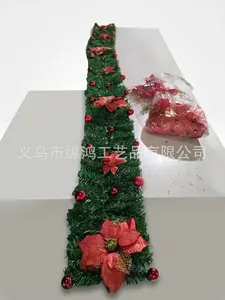 Close-up of green Christmas garland with festive red silk flowers and shiny red ornaments