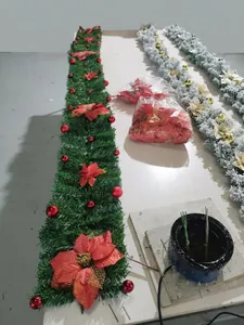 Close-up of green Christmas garland with festive red silk flowers and shiny red ornaments