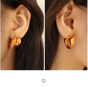 Detailed view of chunky gold heart earrings with polished finish on model's ear
