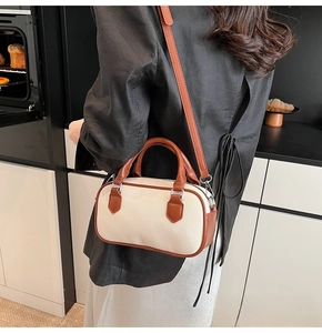 Detailed view of cream canvas bowling bag with brown leather trim worn by model
