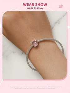 Detail of s925 silver mesh bracelet featuring a pink cat pendant on model wrist